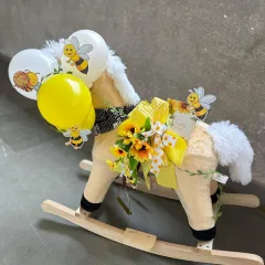 A whimsical and grand gesture for a baby announcement. We've transformed a classic rocking horse into a stunning gift platform, adorned with a bee-themed balloon bouquet and other sweet surprises.