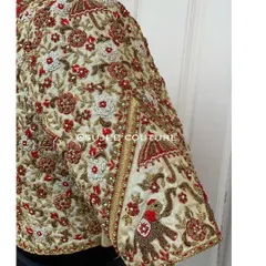 An extreme close-up of hand embroidery on a bridal sleeve. This shot details the zardozi and thread work used to create a traditional wedding procession scene with an elephant motif.