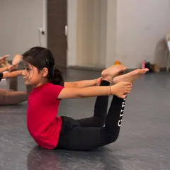 This young dancer holds a perfect bow pose, demonstrating the back flexibility and strength we cultivate in our technical training sessions.
