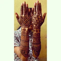 A full-arm bridal henna piece with a prominent criss-cross or 'jaali' pattern on the back of the hands. This style is very popular for its intricate and net-like appearance.