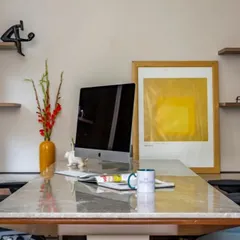 A detail shot of an executive desk, showing how we curate art and decor to personalize a workspace. The clean lines of the desk and shelving are softened by colorful art and personal items.