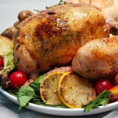 A close-up of our honey, garlic, and thyme glazed roasted chicken. The golden-brown skin and fresh lemon garnish highlight the care and technique we put into our main courses.