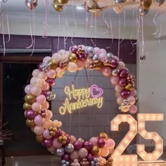 For this 25th anniversary party at home, we created a beautiful focal point with a full balloon ring in shades of pink, rose gold, and silver. The "Happy Anniversary" neon sign and large light-up marquee numbers for the milestone year made the space feel special and festive.