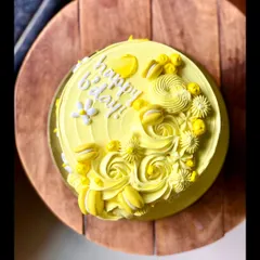 A beautiful yellow Rasmalai cake. This flavor is an Indian dessert classic, reimagined as a cake and decorated here with mini macarons and buttercream swirls.