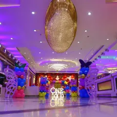 Another perspective of the banquet hall for Kavya's party, showing the entrance walkway decorated with butterfly-themed balloon pillars.