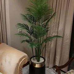 An elegant artificial areca palm in a decorative black and gold pot, placed in a living room corner. It adds a touch of tropical sophistication to the home decor.