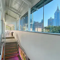 A view from the upper level of the Museum of Art and Photography (MAP) looking out towards the Bengaluru skyline. The circulation spaces are designed to be open and transparent, constantly connecting visitors back to the city context outside.