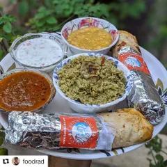 This is what a meal from my cook house looks like when served at home. You can see the rich biriyani rice, bowls of spicy salan and fresh raita, and our foil-wrapped rolls, ready to be enjoyed. It’s a taste of tradition, delivered right to you.