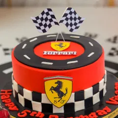 A close-up of the Ferrari-themed cake, showing the checkered flags and iconic logo on a racetrack.