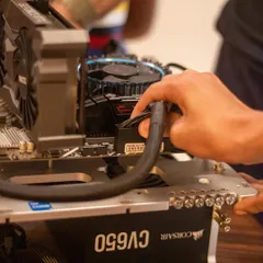 A student carefully connects power cables to the motherboard of a gaming PC. This is a hands-on lesson in cable management and understanding how different components get power.