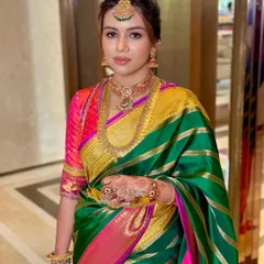 A mid-shot focusing on the harmonious balance between the makeup, the intricate gold jewellery, and the bright colours of the silk saree.