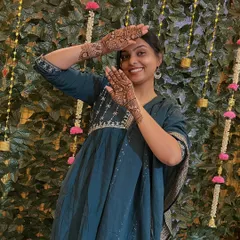 A happy client posing against a beautiful floral backdrop at her mehndi event. Her smile and the lovely henna on her hands are what make my work so fulfilling.