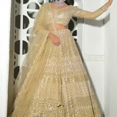 A model posing in the all-gold lehenga, showcasing its full-sleeve design and flattering silhouette against a modern backdrop.