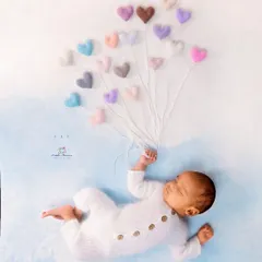 This is an example of a whimsical and creative setup. I used soft, felted hearts as balloons to create a sweet, imaginative story, showing how props can add a touch of playful magic to a newborn photo.
