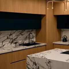 A close-up of the Bangalore kitchen, highlighting the bold black and white marble on the countertop and backsplash. The contrast with the warm wood veneer and sleek black cabinets creates a dynamic and stylish space.