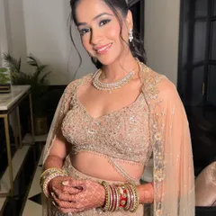 A stunning and delicate reception look. The makeup is soft and romantic, with a gentle shimmer on the eyes and a nude-pink lip, perfectly complementing her beige embellished lehenga.