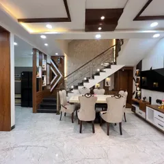 This angle captures the harmony between the dining area, staircase, and living space. We used a consistent palette of warm woods, neutral tones, and marble flooring to create a cohesive flow throughout the open-plan layout.