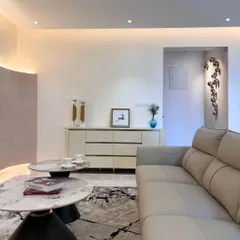 A wider view of the living room, showing how the sleek marble coffee tables and minimalist side cabinet complement the stylish and functional TV wall.