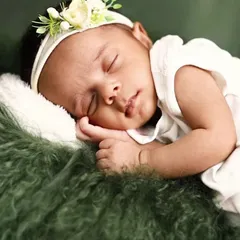 A close-up of a sleeping newborn resting on a soft, green fur blanket. We focus on capturing the peaceful expressions and tiny details, like their hands and lips.