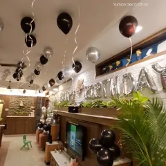 A view of the room decoration from another angle, showing the "Happy Birthday" foil balloon banner above the main seating area.