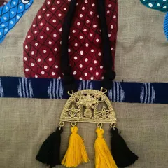 The third piece from the Dokhra collaboration, featuring a black cord with playful yellow and black tassels that highlight the traditional motifs in the pendant.