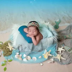 Our little mermaid dreaming by the shore. I create a realistic beach scene in your home, complete with sand, shells, and a gentle ocean backdrop, for a magical seaside portrait.