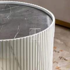 A close-up of the fluted coffee table, showing the intricate texture of the base and the beautiful veining of the dark marble top.