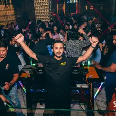 Both hands in the air, celebrating a massive beat drop with the audience.