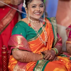 The smile says it all. This bride is glowing in a traditional Kashibai-style Nauvari, looking like a dream in a vibrant orange and green combination for her wedding day.