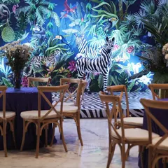 The jungle theme extended to the seating areas, where rustic wooden chairs were set against the vibrant backdrop, creating a cohesive look for the entire event space.
