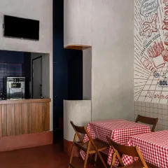 This view shows the interplay of different elements: the bold graphic mural, the clean white tiles, the warm wooden counter, and the deep blue ceiling. The layout provides a mix of table seating and counter space to accommodate different guest needs.
