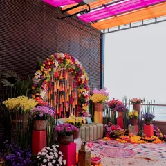 The stunning and colorful decor setup for a Mehendi carnival, featuring a floral arch and vibrant seating.