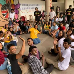A shot of our community sitting in a circle at Sign Fest. This image captures the spirit of togetherness and shared learning, with everyone waving, a common sign of applause in the Deaf community.