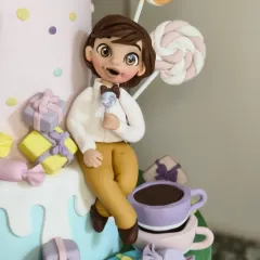 The equally detailed boy figurine from the Candyland cake, enjoying a lollipop. His cheerful expression and dapper little outfit add to the whimsical charm of the whole piece.