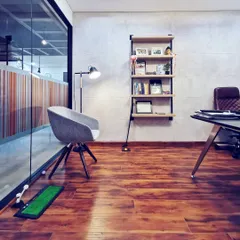 A view into a leader's cabin, designed to be sleek, adaptive, and responsive. The space combines hardwood floors, a concrete-finish wall, and glass partitions, with personal touches like a golf putting green to reflect a modern leadership style.