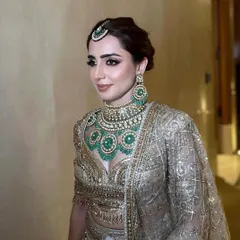A close-up of a sophisticated bridal updo, designed to complement heavy jewelry and a maang tikka. The hair is swept back cleanly, ensuring a polished and regal look for the wedding day.