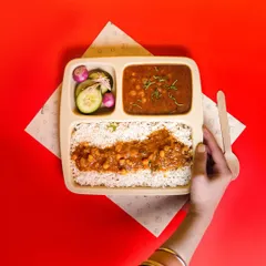 A top-down shot of a chole rice meal-box against a bold red background. This clean, graphic style is perfect for food delivery menus and apps.
