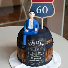 A special cake for a father's 60th, designed to look like a vintage whiskey barrel. It features a custom "Aged to Perfection" label and a fondant figurine of the man of the hour, with every detail planned meticulously by his daughter.