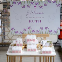 Another view of the Baptism welcome table, showing the custom-designed sign and beautifully arranged party favors for guests.