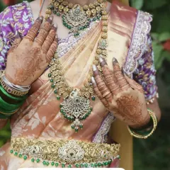 For a touch of royal elegance, I offer Victorian-style antique jewellery. This close-up shows the beautiful detail in the choker, long necklace, and waist belt, all studded with green stones to perfectly complement a silk saree.