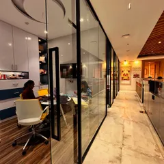 Transparency and connection are key in a modern office. Here, glass partitions for private cabins create a sense of openness, allowing natural light to flow through the space while maintaining a clear view of the office's central design narrative.