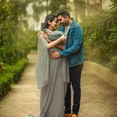 A new mother and father touch foreheads as they lovingly cradle their newborn baby between them. This intimate outdoor portrait is filled with emotion and the magic of new parenthood.