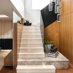 For this South Ex apartment, we designed a modern staircase with soft beige marble steps and a sleek black metal railing. A contemporary chandelier hangs in the double-height volume, drawing the eye upward.