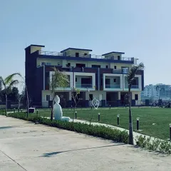 A view of the completed row houses at our Kanpur project, set against a large community lawn. The design of the homes is uniform yet modern, creating a harmonious streetscape, while the open green space with a Buddha statue promotes a tranquil atmosphere.