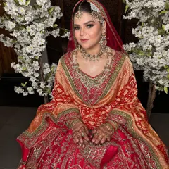 A full view of this beautiful bride in her red and orange lehenga. The makeup is designed to harmonize with the warm tones of her outfit, creating a cohesive and stunning bridal appearance.