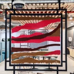 The tapestry panel during the installation process. You can see how the piece is designed to be semi-transparent, allowing light to pass through while still providing a sense of division and privacy.