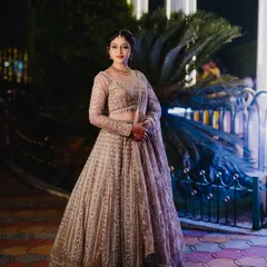 A full-length shot of a bride in her shimmering beige lehenga. The makeup is a sophisticated soft glam with a defined eye and neutral lip, designed to complement the intricate outfit for her reception.