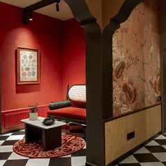 An arched entryway frames a dramatic red seating nook in our showroom. The design plays with sightlines and color blocking, using a squirrel-patterned wallpaper to add a touch of whimsy.