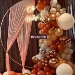 A chic and modern "Oh Baby" shower with a boho feel. The circular gold frame is draped with fabric and a stunning organic balloon garland in rust, peach, and white tones.