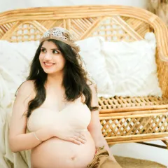 A happy, relaxed moment during a natural-themed studio shoot. This portrait captures the unfiltered joy and beauty of pregnancy.